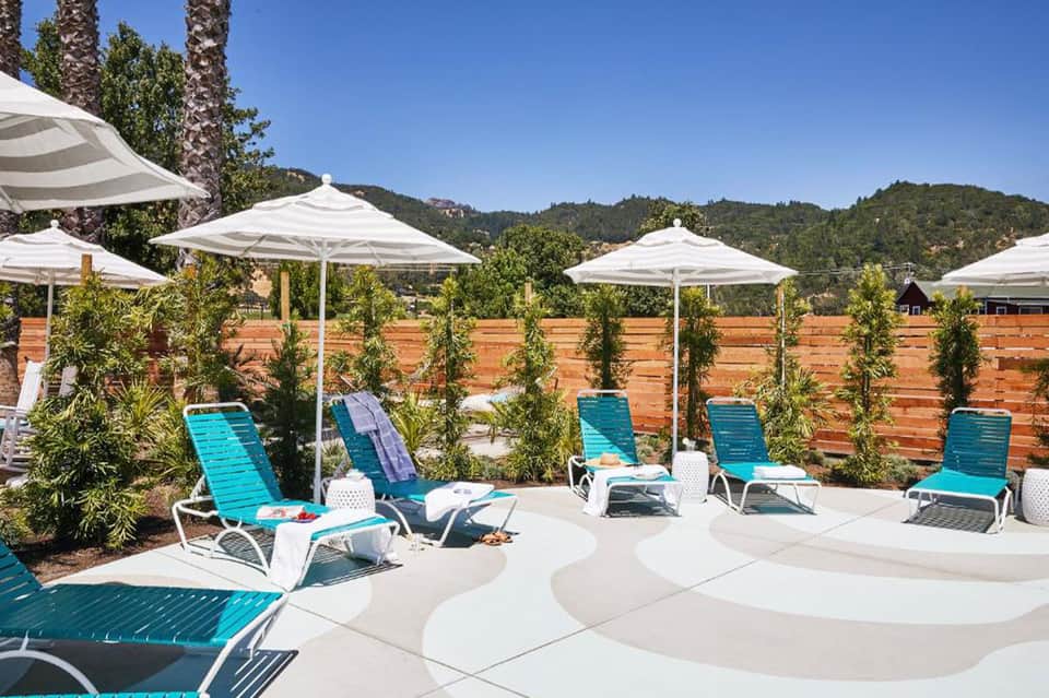Pool area with turquoise loungers under white umbrellas and mountain backdrop
