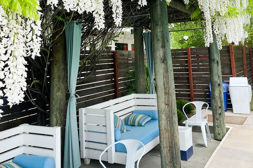 Beachfront cabana with white beds, cascading white flowers, and ocean views