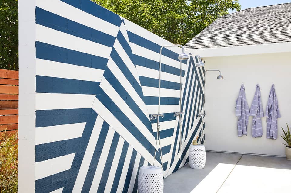 Outdoor shower area with navy striped privacy screens and towels