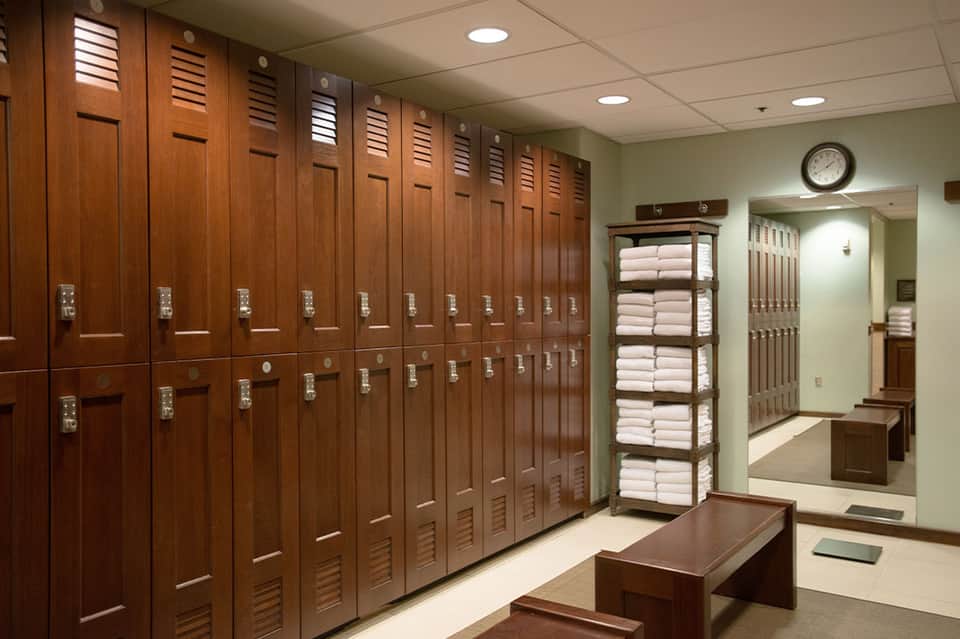 Spa locker room with wooden storage lockers, white towels, and mirror in wellness facility