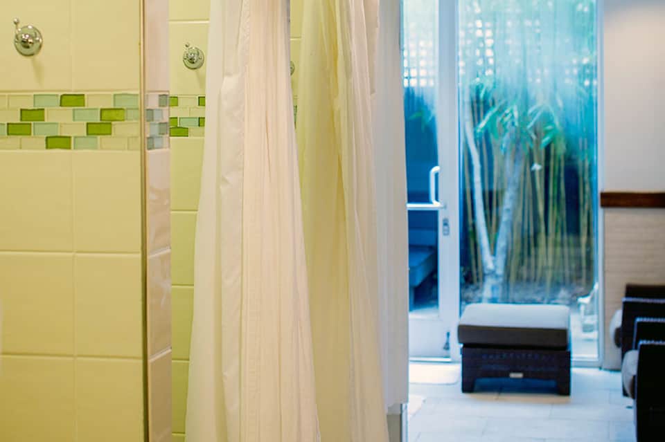 Hotel bathroom with yellow tile walls and glass shower enclosure with aquatic design