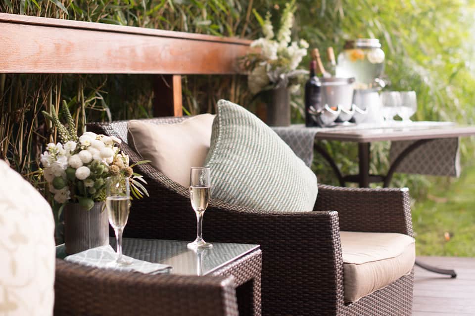 Elegant patio seating with champagne glass, flowers, and garden views