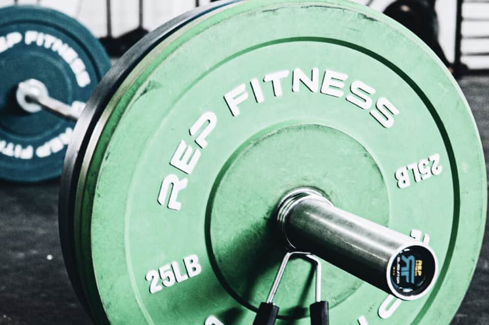 Green weight plates labeled Rep Fitness stacked at a fitness facility