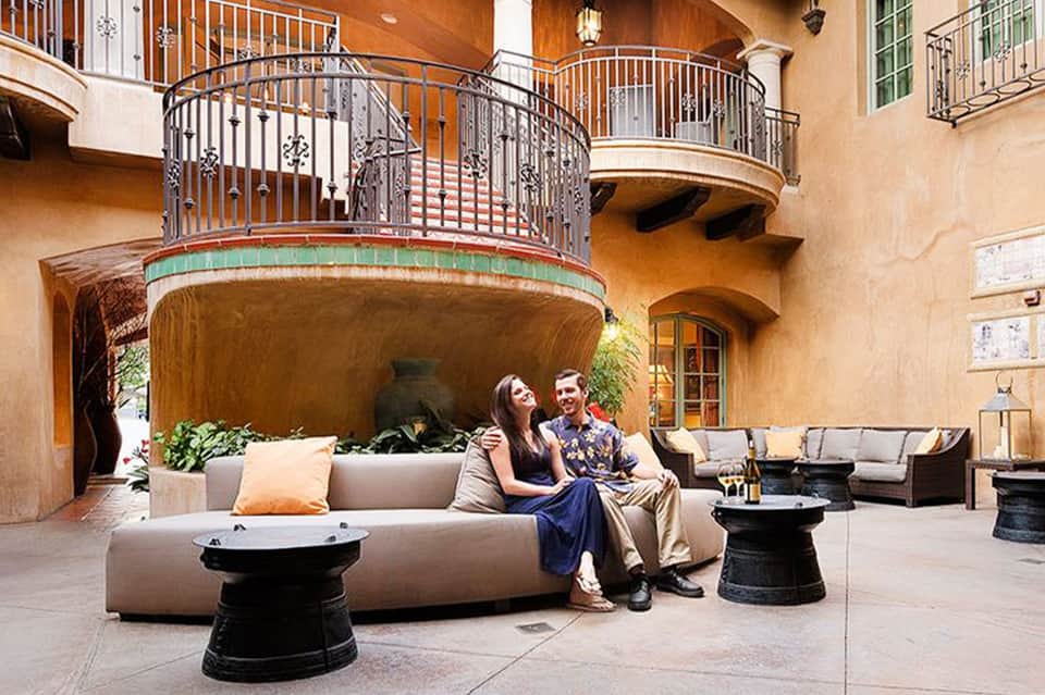 Courtyard lounge with curved seating, curved balcony railings, and warm stucco walls