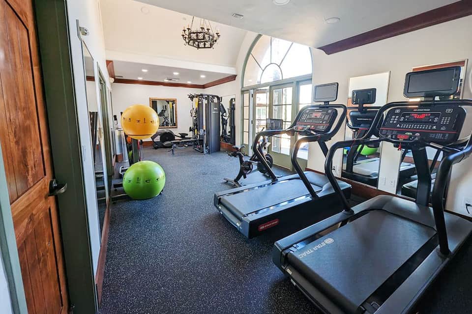 Bright fitness center with treadmills, exercise equipment, and natural light from arched windows