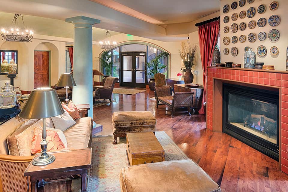 Elegant resort lobby with fireplace, decorative plates, and eclectic furnishings
