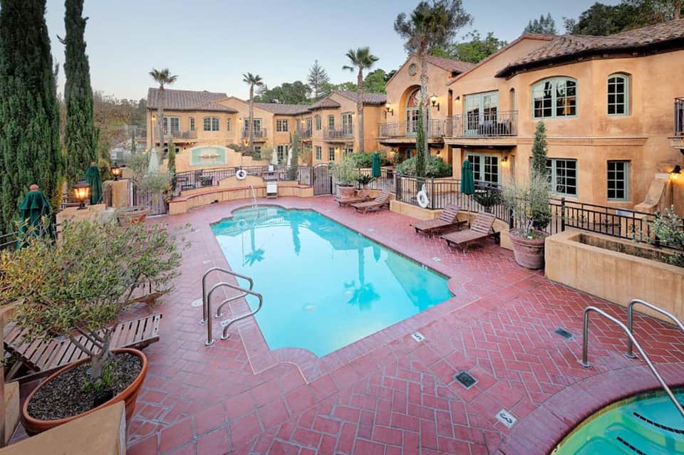 Mediterranean-style resort courtyard with terracotta pool, arched architecture, lounge chairs, and landscaping