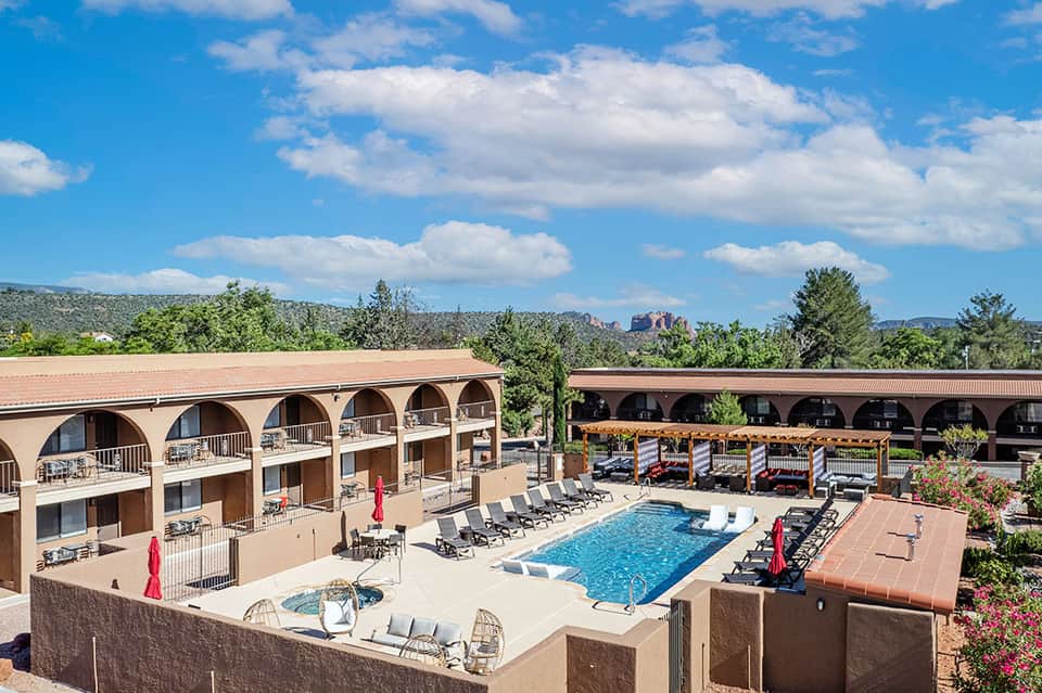 Resort courtyard with pool, lounge chairs, and arched architectural design in desert landscape