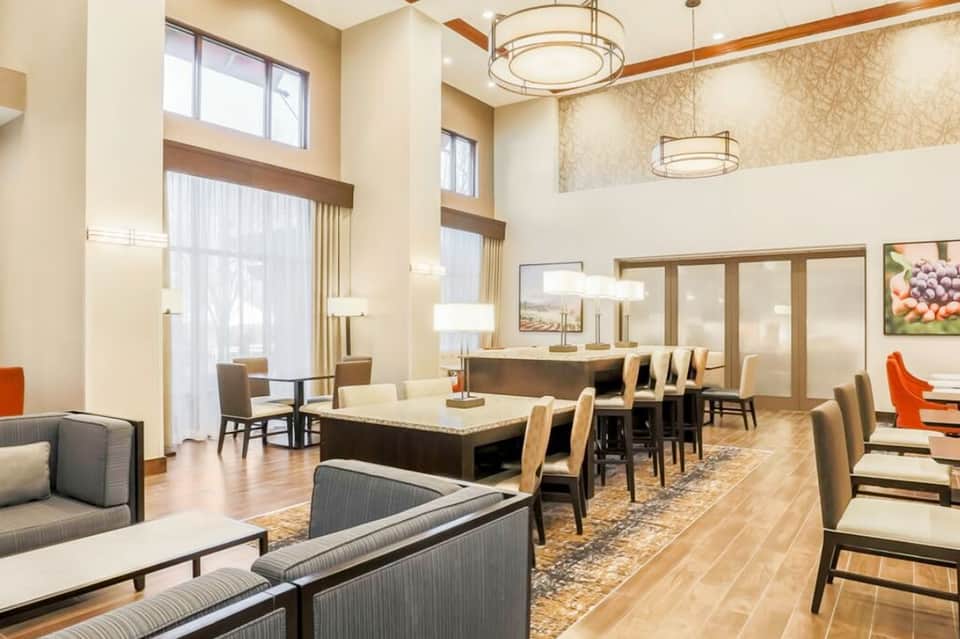 Bright hotel lobby lounge with wood accents, seating areas, and reception desk