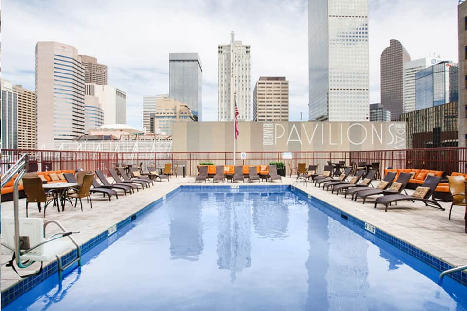 Urban rooftop pool at Pavilions with city skyline backdrop, loungers, and umbrellas