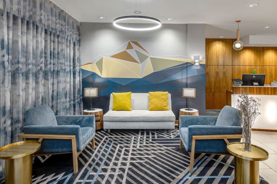 Modern hotel lobby with geometric art wall, contemporary furnishings, and wood accents