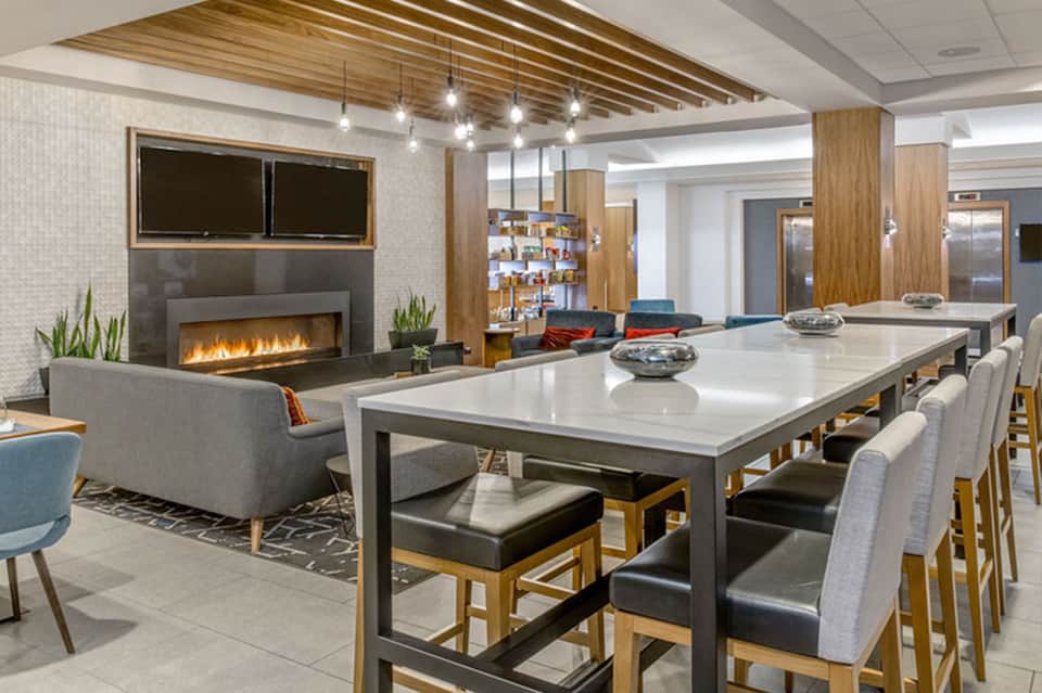 Modern resort common area with fireplace, dining table, wood ceiling, and contemporary furnishings