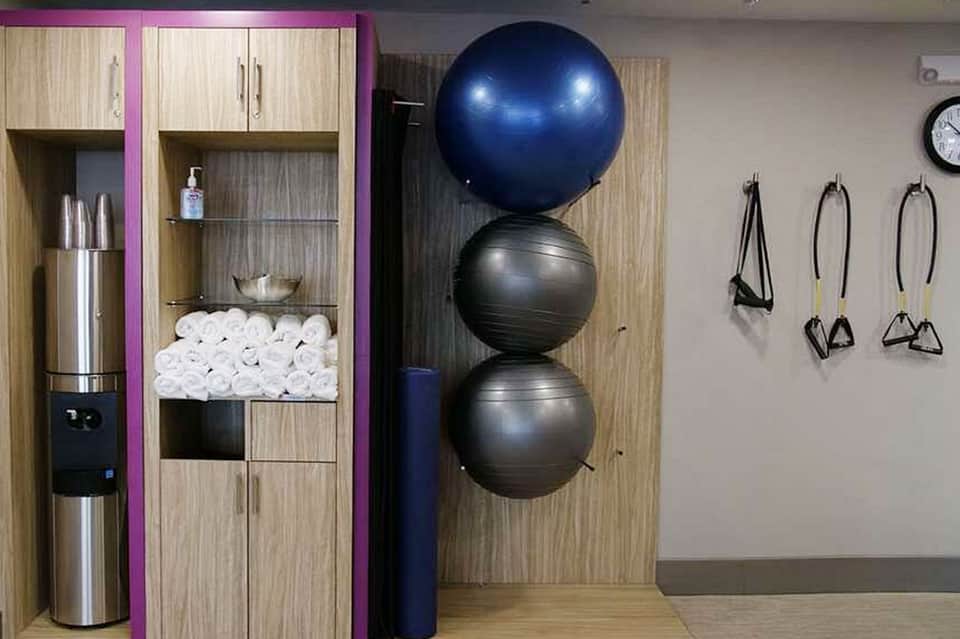 Fitness center with exercise balls stacked vertically, storage cabinets, water dispenser, and equipment