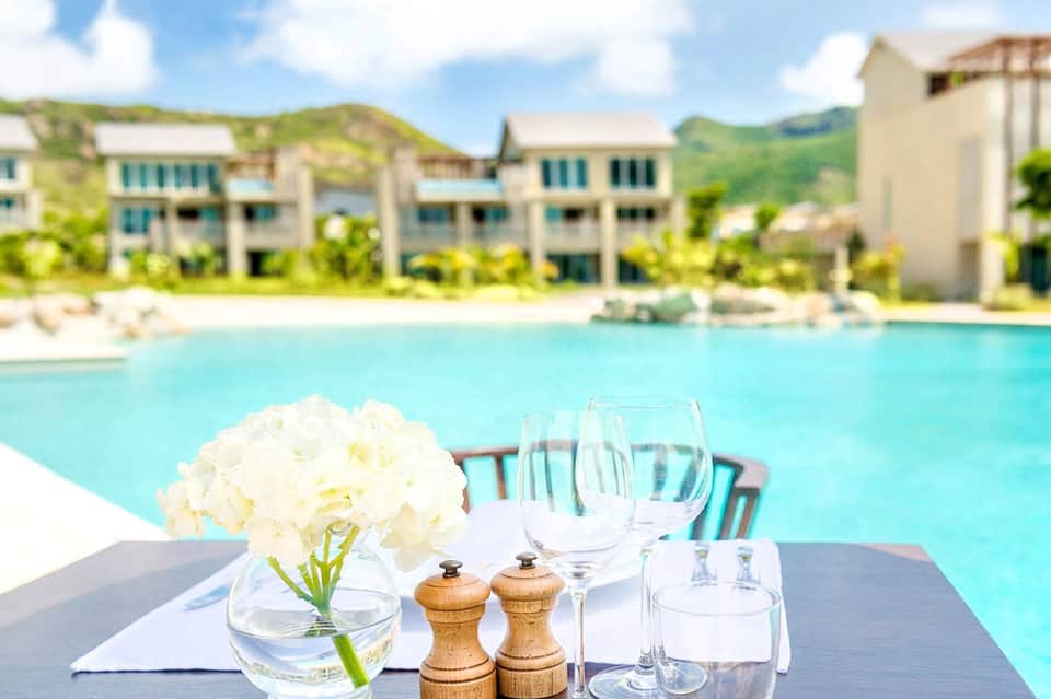 Elegant poolside dining setup with white flowers, wine glasses, and mountain views beyond the resort