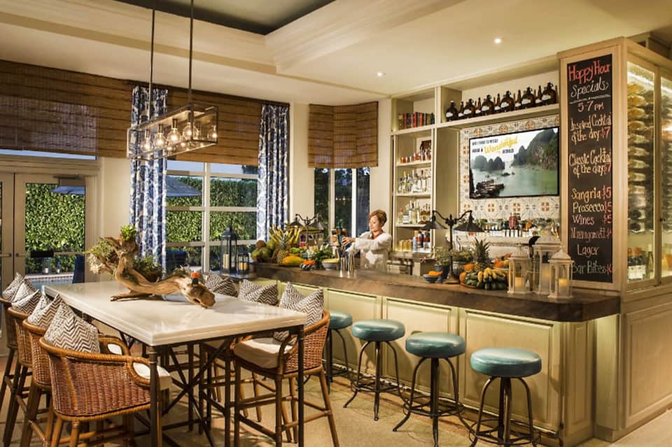 Upscale bar interior with large windows overlooking ocean, rattan chairs, and tropical décor