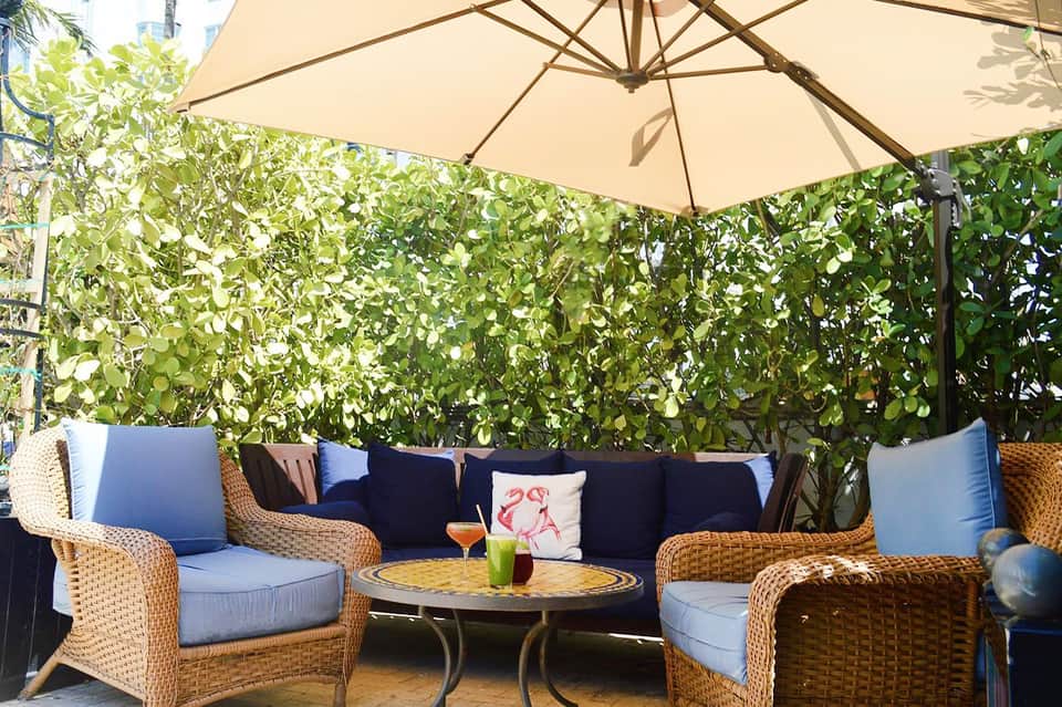 Outdoor lounge seating area with wicker furniture, cushions, and shade umbrella