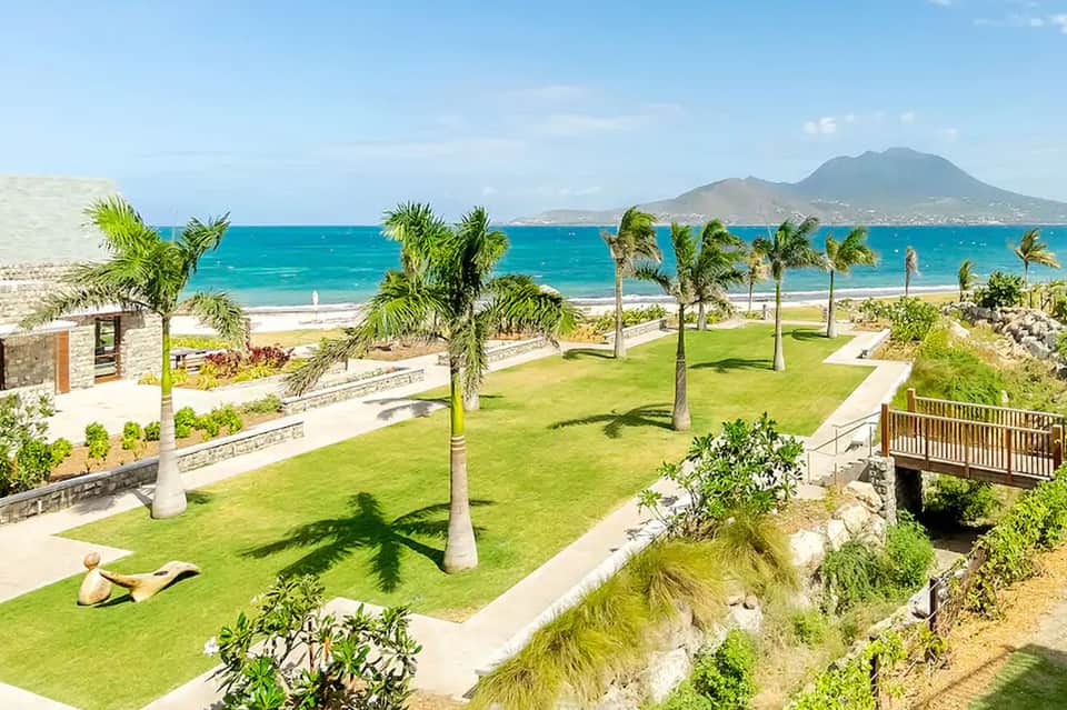 Beachfront resort grounds with palm trees, manicured lawn, and ocean view with volcanic mountain