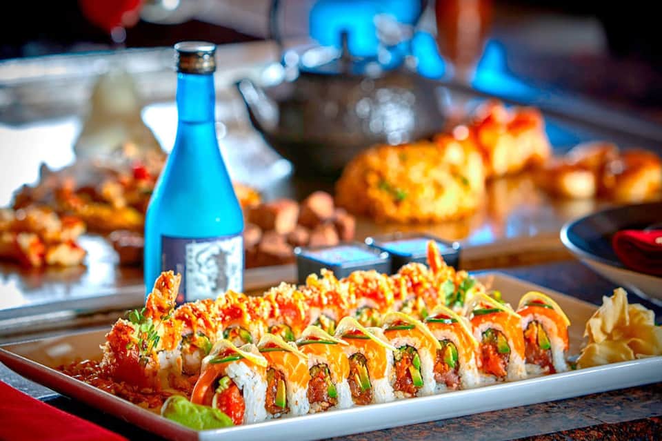 Gourmet sushi platter with blue bottle and tropical dining setup