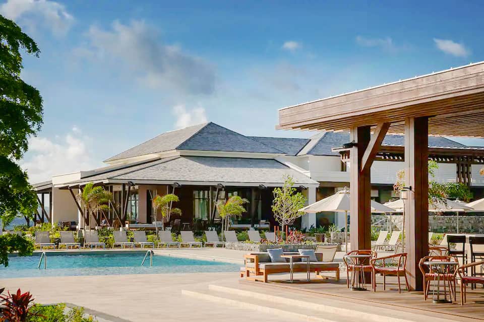 Modern resort pool area with wooden pergola, lounge seating, and contemporary architecture