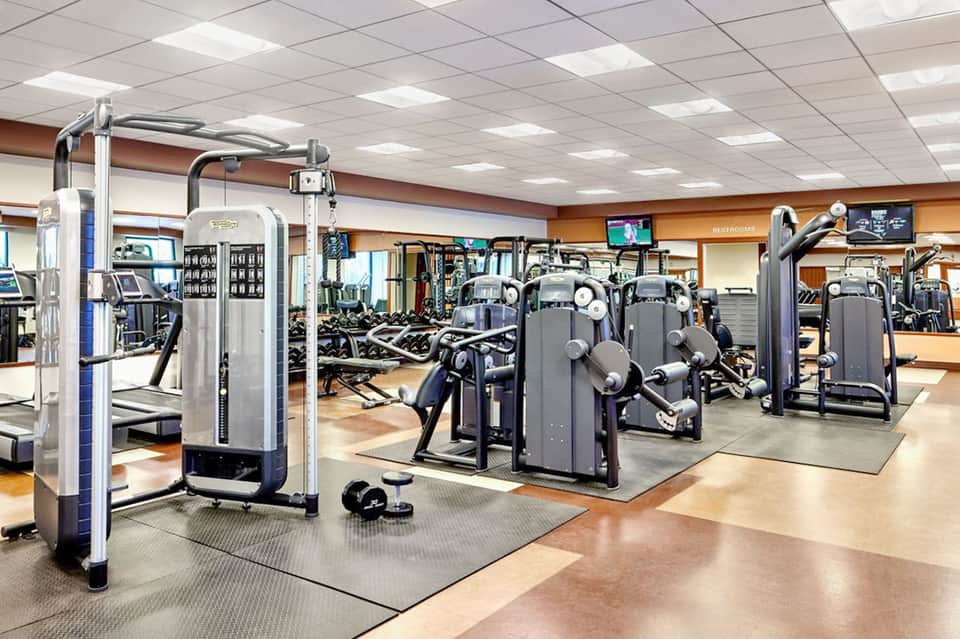 Fitness center with cardio equipment and weight machines under bright ceiling lights