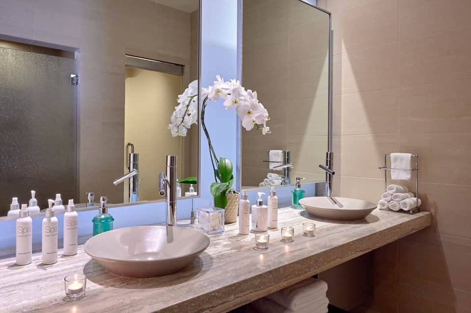 Luxurious bathroom with dual vessel sinks, white orchids, and marble countertop