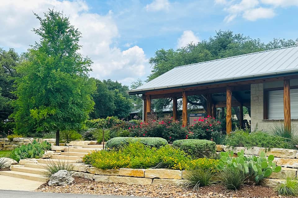 Modern ranch-style building with metal roof, wooden posts, and xeriscape landscaping with succulents
