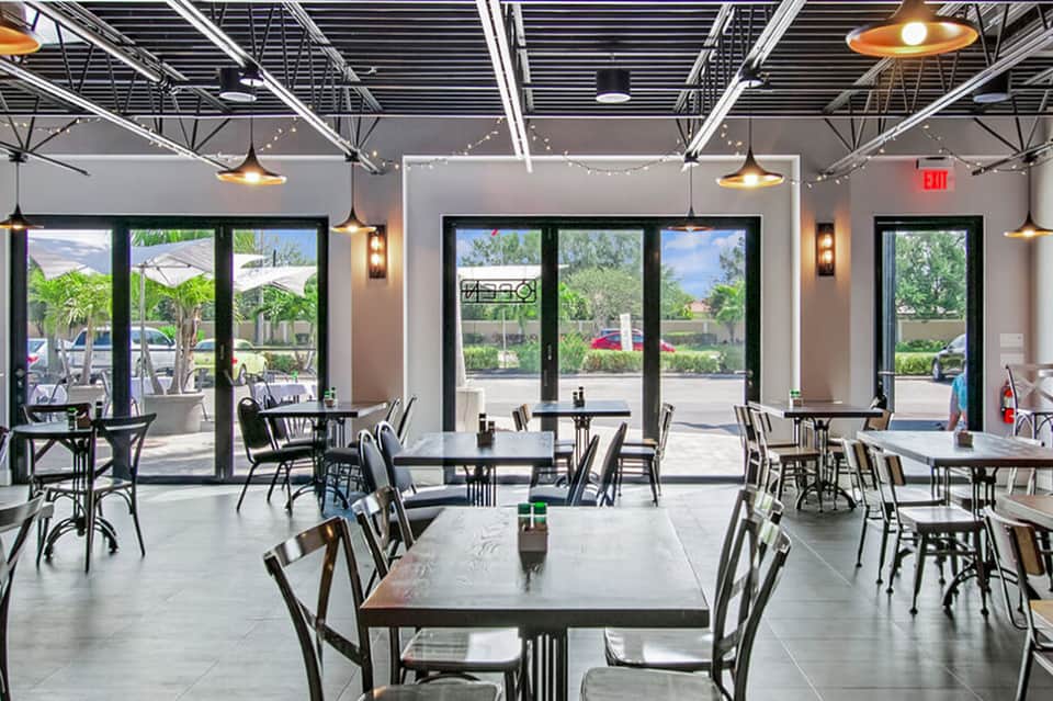 Modern casual dining space with industrial ceiling, pendant lights, and outdoor patio view