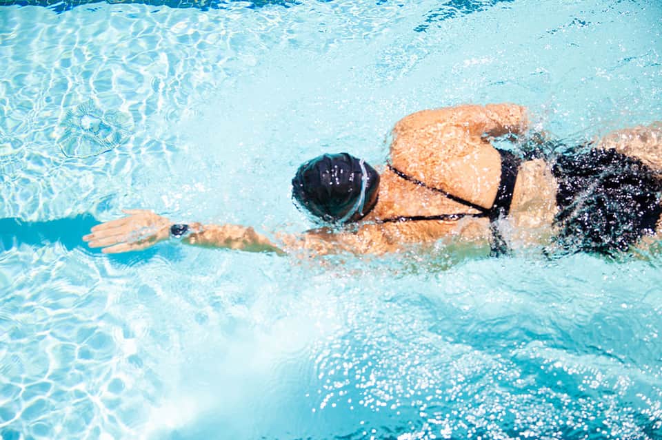Swimmer doing butterfly stroke in crystal clear turquoise pool with rippling water surface