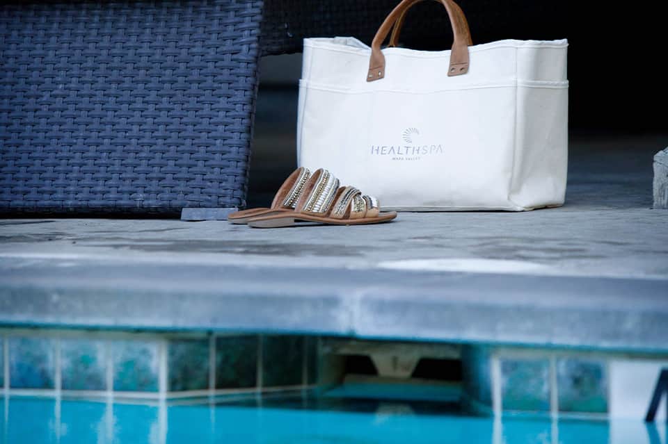 White spa tote bag and striped sandals displayed poolside at luxury resort wellness center