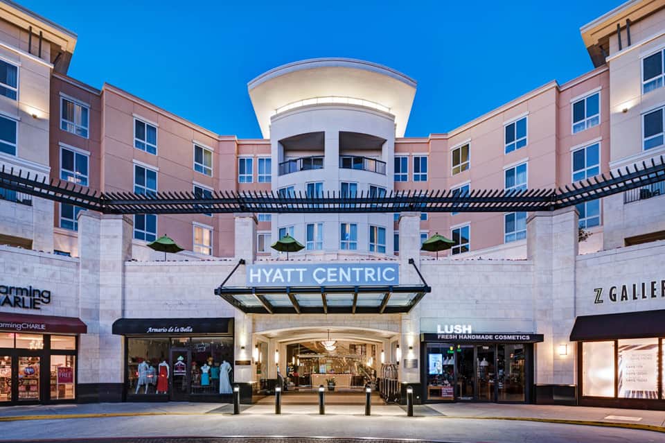 Hyatt Centric hotel entrance with pink exterior and retail shops at street level