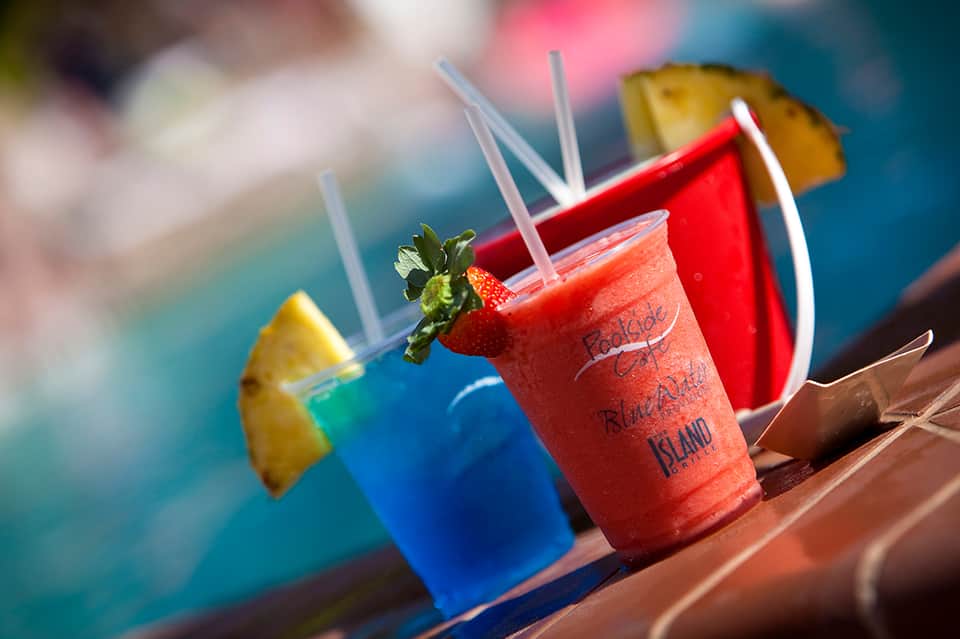 Colorful tropical drinks by pool with strawberry garnish and branded cup