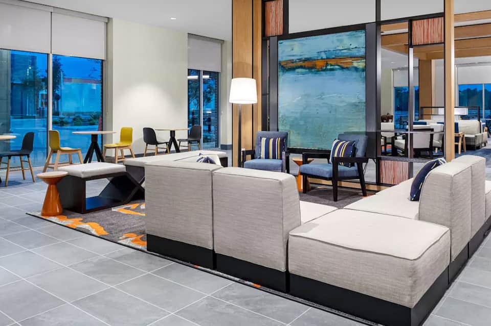 Modern hotel lounge with cream seating, floor-to-ceiling windows, ocean views, and wood accents