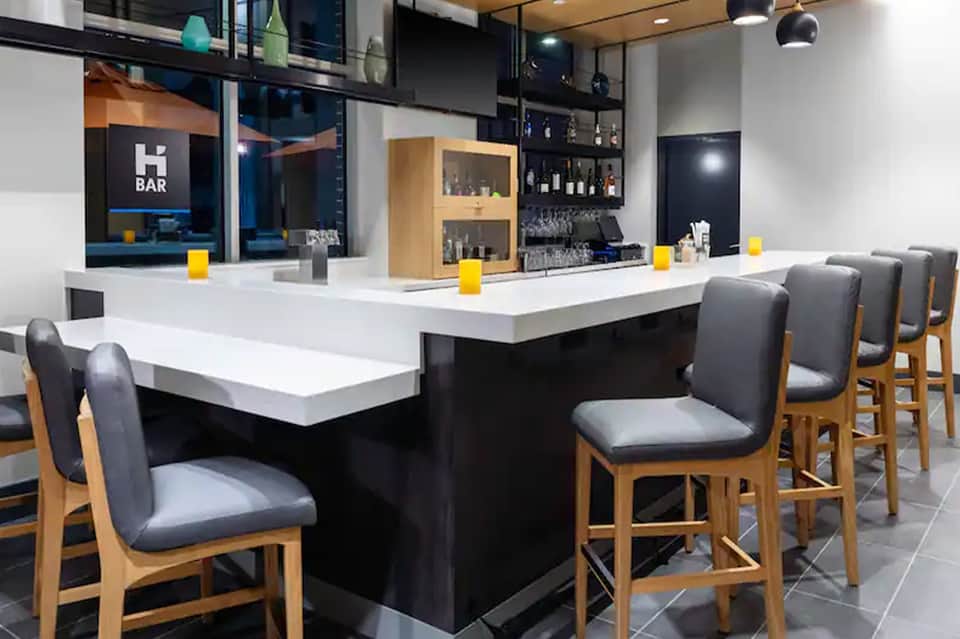 Modern bar with white counter, wooden barstools, and blue neon 'BAR' sign