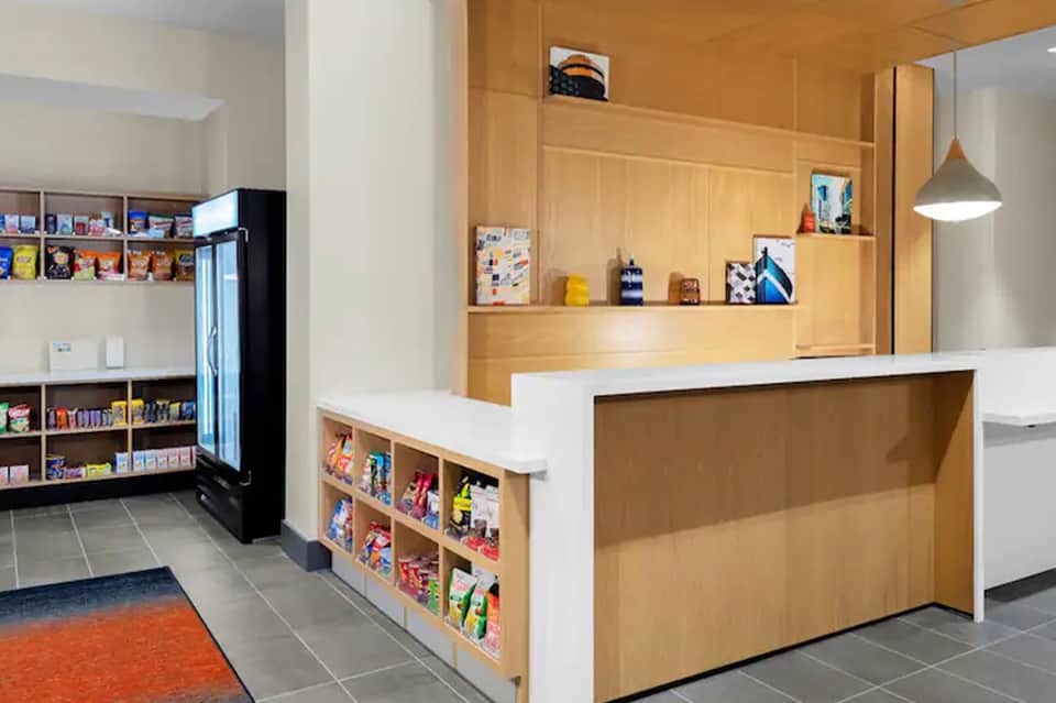 Contemporary hotel lobby with light wood paneling, convenience shop, and modern reception desk area