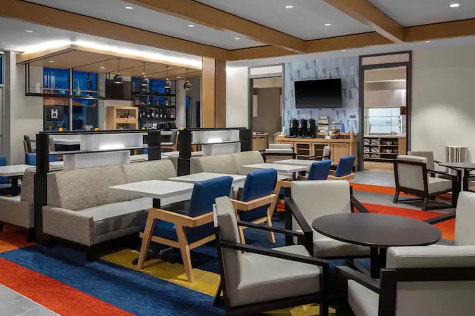 Modern resort lobby lounge with contemporary seating, bar area, and colorful geometric floor pattern
