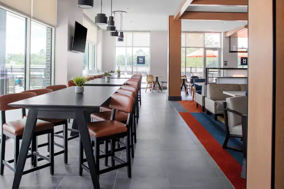 Modern resort lounge with high-top dining table, brown leather chairs, and large windows