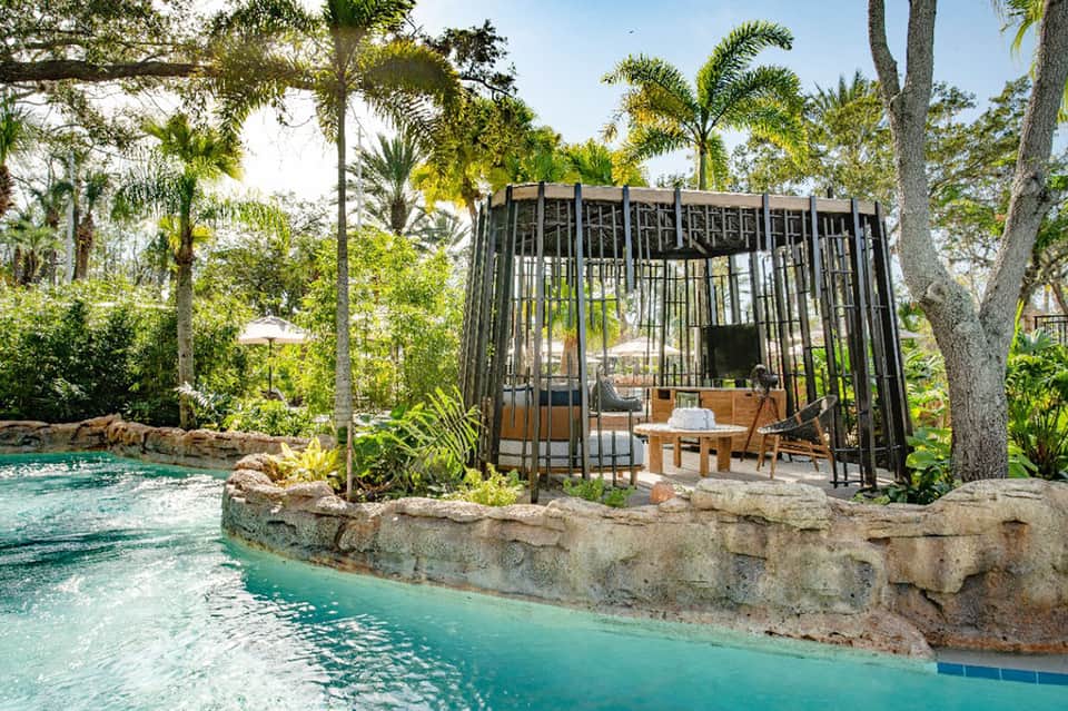 Luxurious spa pavilion by turquoise pool surrounded by tropical palm trees