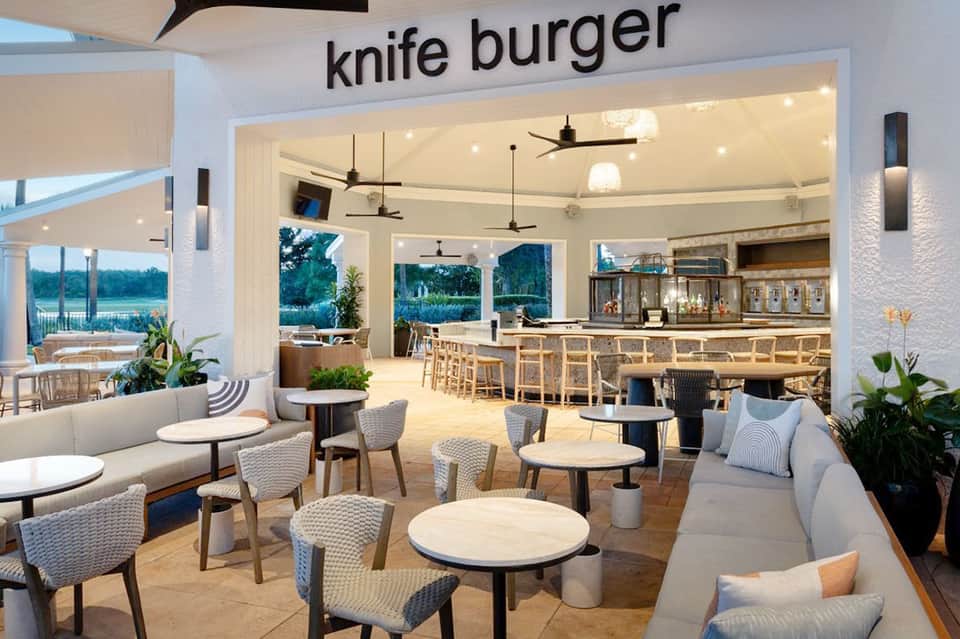 Open-concept knife burger restaurant with waterfront views, bar seating, and modern coastal dining design