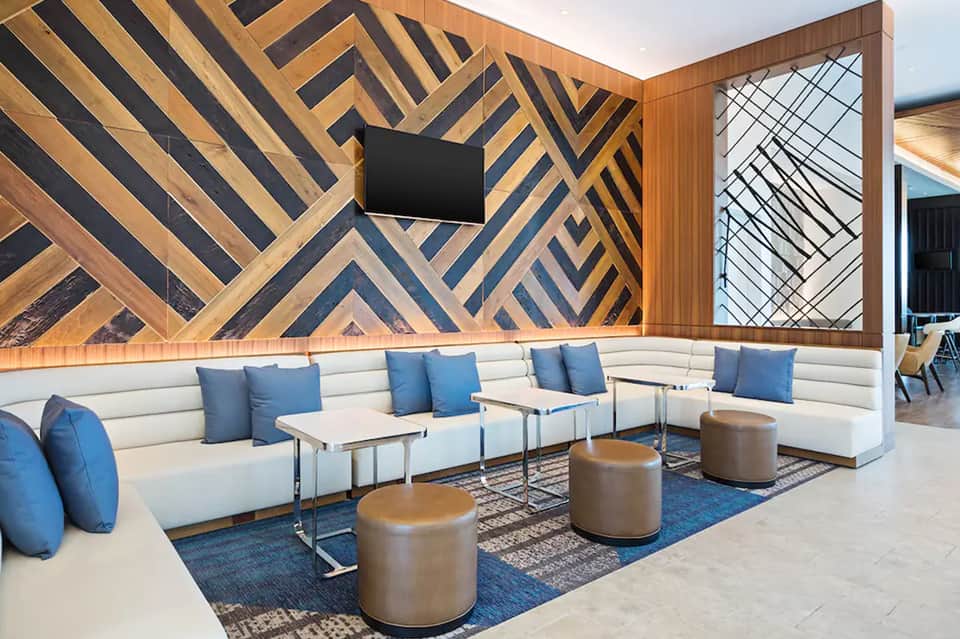 Modern hotel lounge with geometric wood wall pattern, white sectional sofa, and blue accents
