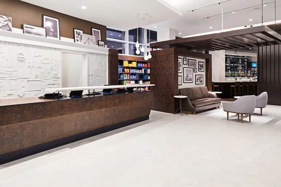 Contemporary hotel lobby with brown cork accent wall, reception desk, and modern seating area