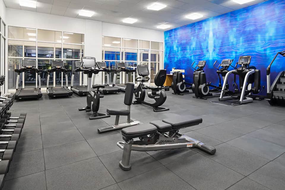 Fitness center with treadmills, exercise bikes, and blue water-themed wall mural