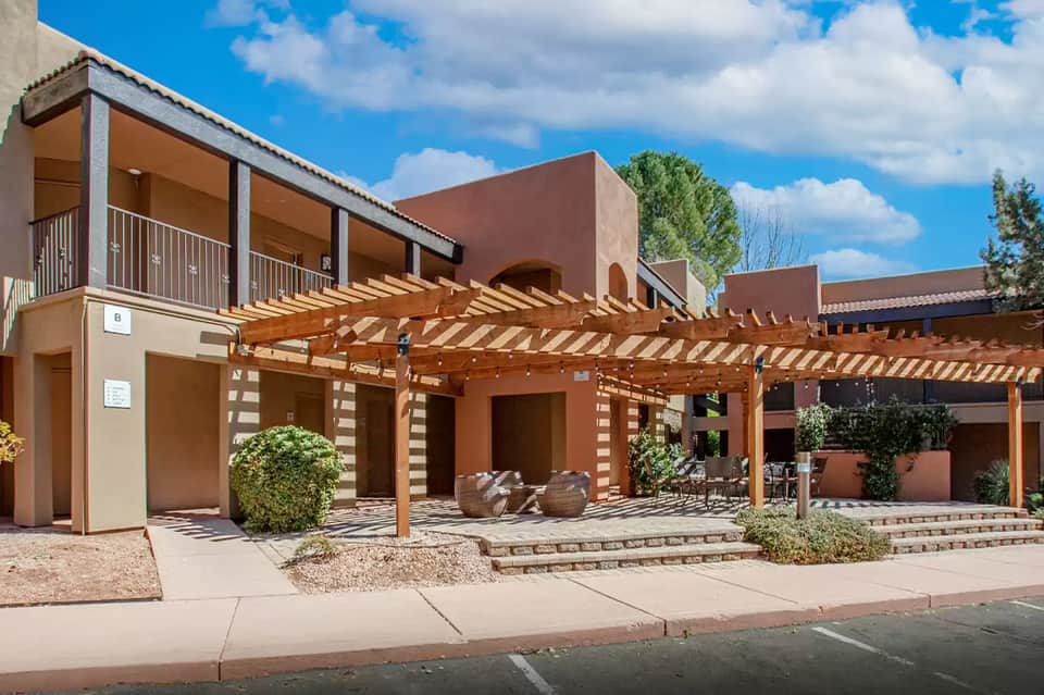 Modern terracotta-colored resort building with wooden pergola, terrace, and desert landscaping