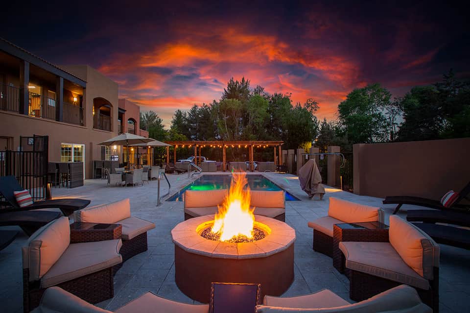 Luxury resort courtyard with fire pit, lounge seating, and glowing pool at dusk