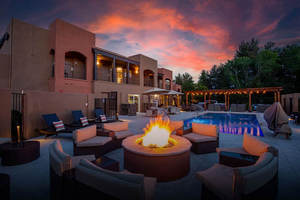 Resort fire pit lounge at twilight with Southwestern architecture, seating, and glowing pool