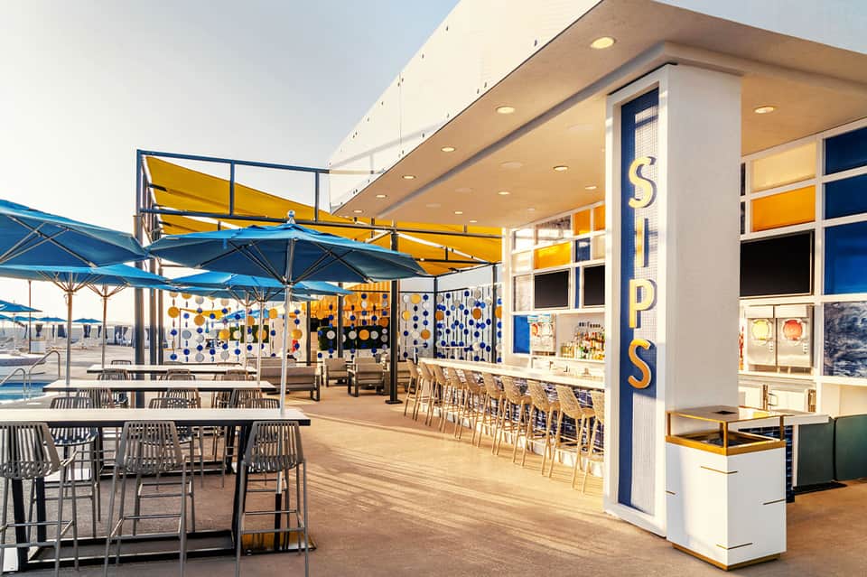 Modern resort bar and grill with blue umbrellas, yellow accents, and ocean view