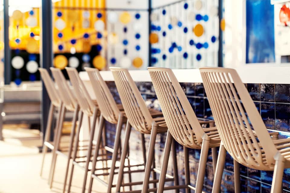Modern pool bar with neutral-toned chairs and blue and yellow polka dot backdrop