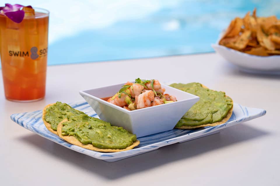 Avocado toast and shrimp ceviche with tropical drink poolside