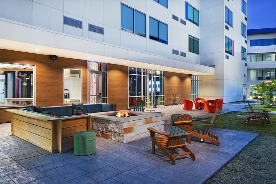 Modern resort courtyard with fire pit, lounge seating, and contemporary architecture