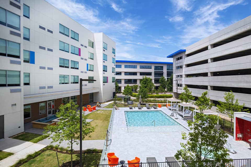 Courtyard pool surrounded by modern apartment buildings with orange seating areas