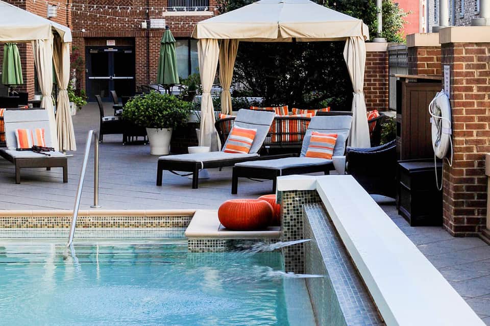 Rooftop pool area with gazebos, loungers, and orange accent pillows